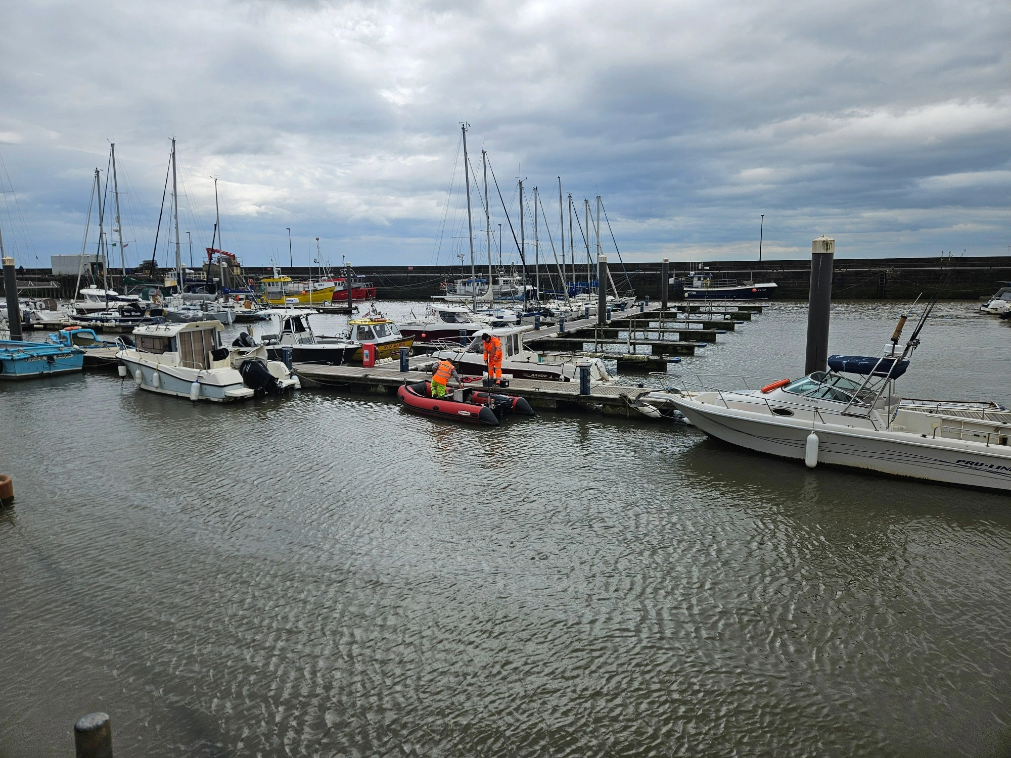 MHLS land surveyors at bridlington harbour on a cloudy day surrounded by boats.